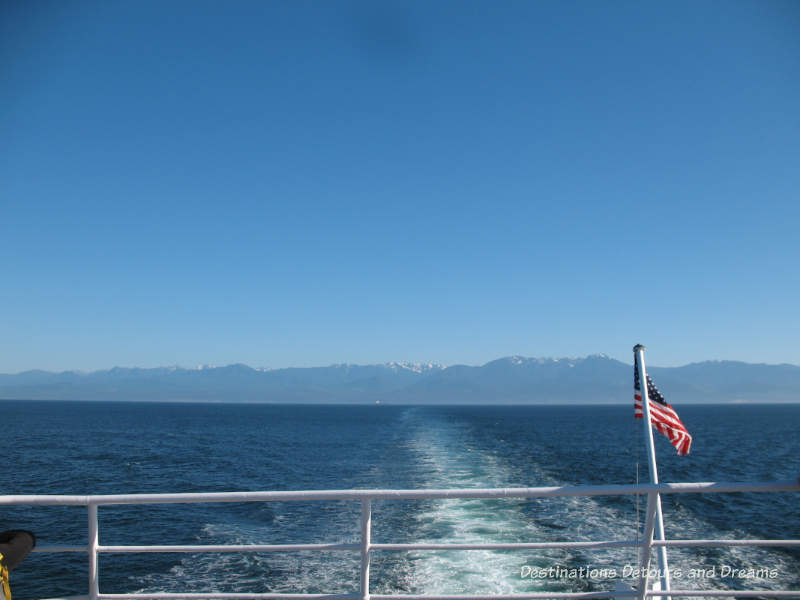 View of Salish Sea looking out the back of the Black Ball Ferry, mountains in the background