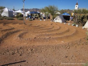 Sundial in the sand with craft vendor tents in background, Superstition Mountain Museum