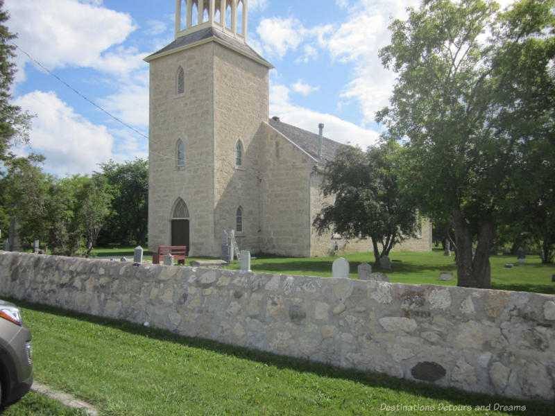 Stone church surrounded by cemetery and a low stone wall