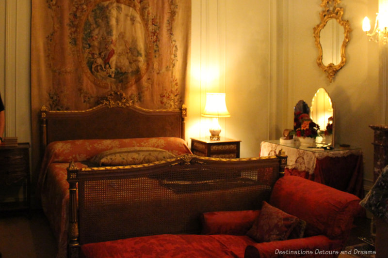 Bedroom with dark wood bedroom, red bed coverings, and red upholstered chaise lounge