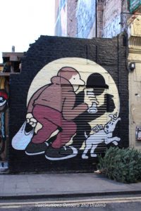 London street art in Brick Lane: shadow of a man and dog in a spotlight, painted by Muretz