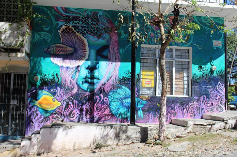 Blue and pink street mural of girl and coral reefs