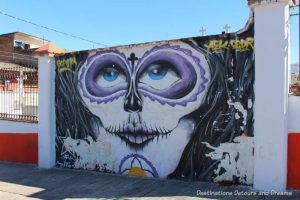 Mural of woman with purple-ringed eyes on the wall of El Panteón Cemetery in Puerto Vallarta