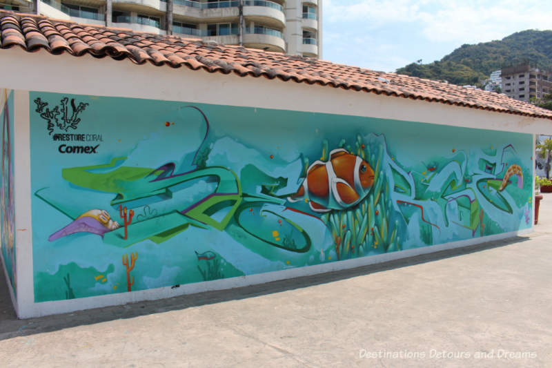 Puerto Vallarta street art: large brown fish trapped in white plastic in the middle of a large turquoise see with reefs