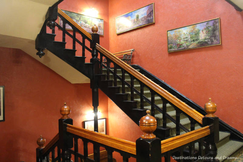 Stairwell with wood-trimmed staircase on art on red coloured walls at Crescent Hotel