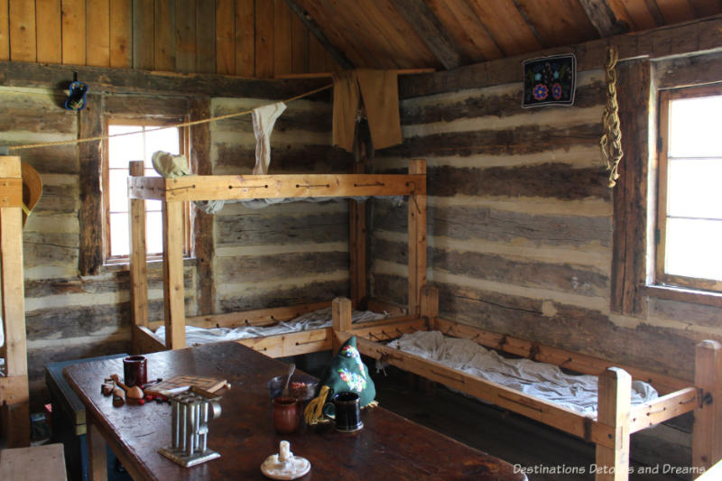 Crude wood cots and a table with games in the voyageur winter cabin at Fort Gibraltar in Winnipeg, Manitoba