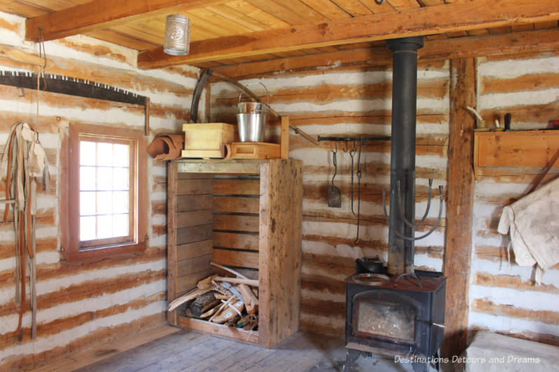 Wood stove, wood stack and items hung on walls in workshop at Fort Gibraltar in Winnipeg, Manitoba