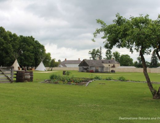 View of field and stone wall and buildings of Lower Fort Garry