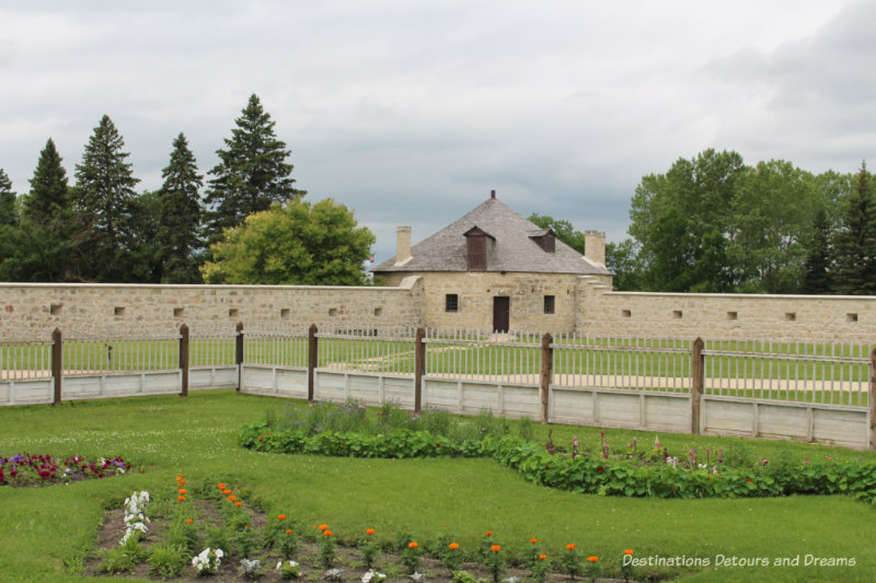 Two sides of the stone wall around Lower Fort Garry with a circular stone bastion at the corner