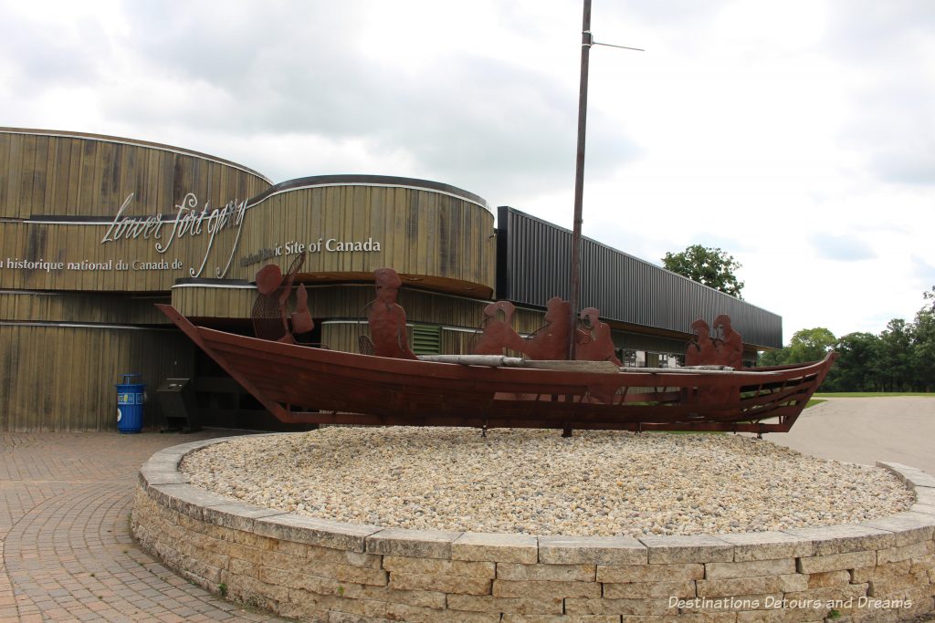 York boat sculpture in front of the flowing lines of the Interpretative Centre of Lower Fort Garry