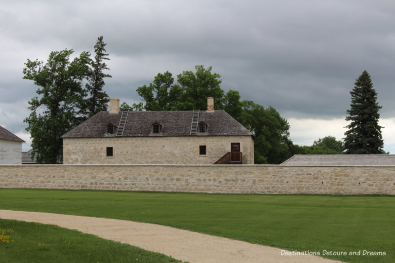 Stone wall of Lower Fort Garry with stone building behind it