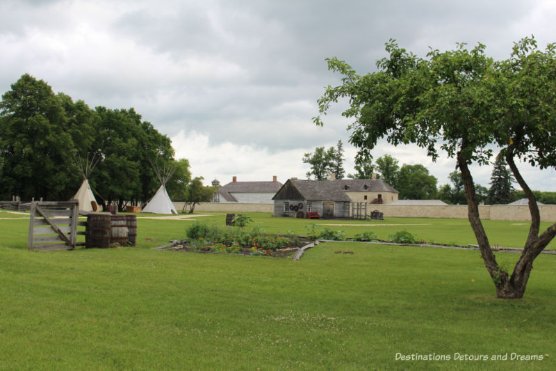 View of field and stone wall and buildings of Lower Fort Garry