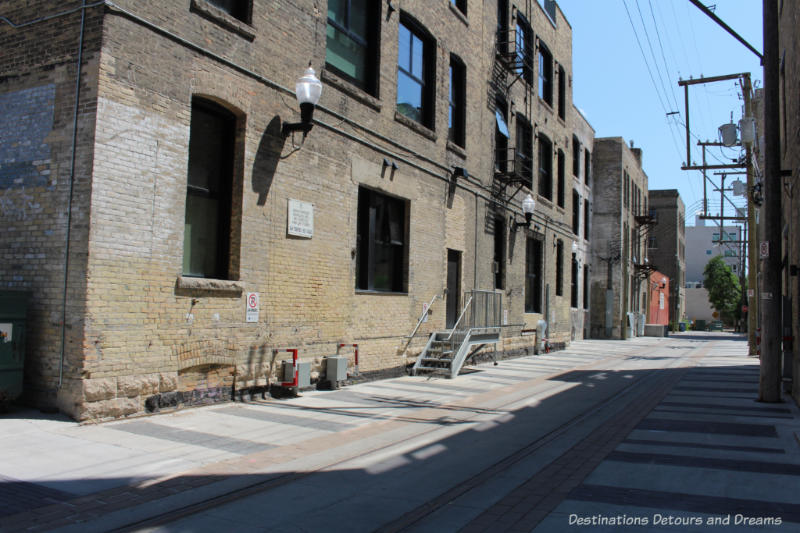 Winnipeg alleyway with railway spur lines and old warehouse loading docks reminds us of Hell's Alley