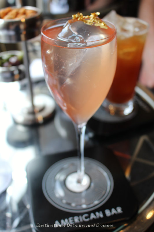 Peach-rose coloured cocktail with gold leaf floating on it at the London Savoy Hotel American Bar