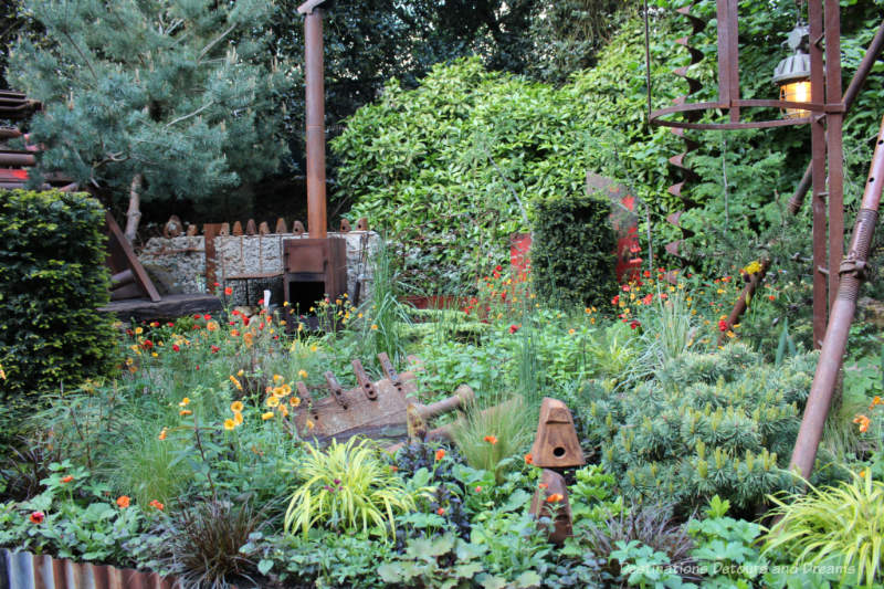 Rusting industrial pieces amid a lush naturalistic garden in the Forgotten Quarry Garden at the 2019 Chelsea Flower Show