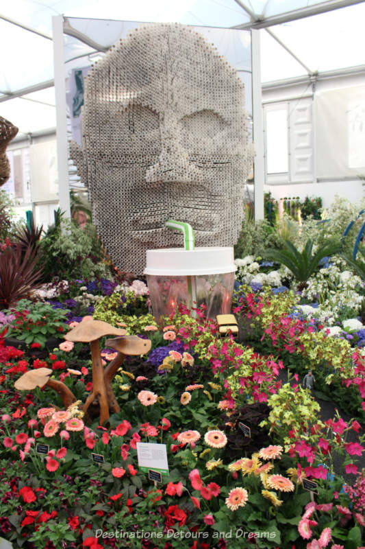 Giant face made out of straws in the Floella's Future display at the 2019 Chelsea Flower Show