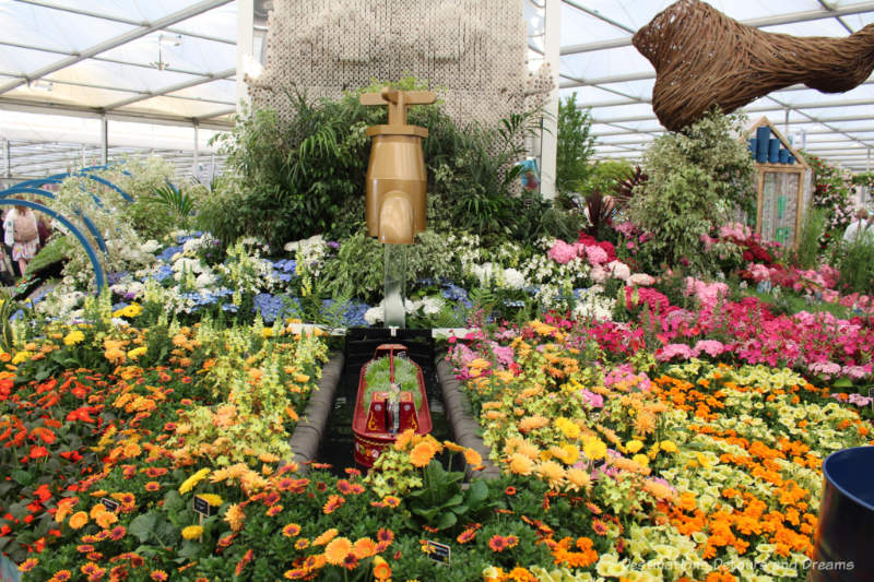 Colourful flowers with small canal and canal boat as part of Floella's Future display at the 2019 Chelsea Flower Show