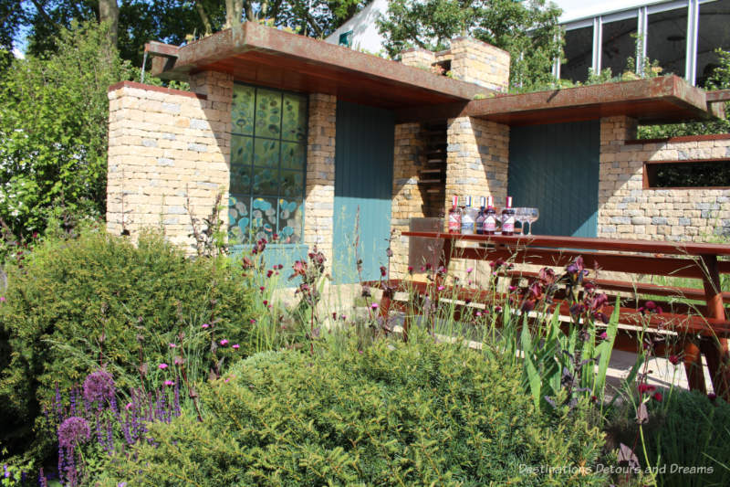 Courtyard with picnic table in a pastoral setting in the Warner's Distillery Garden at the 2019 Chelsea Flower Show