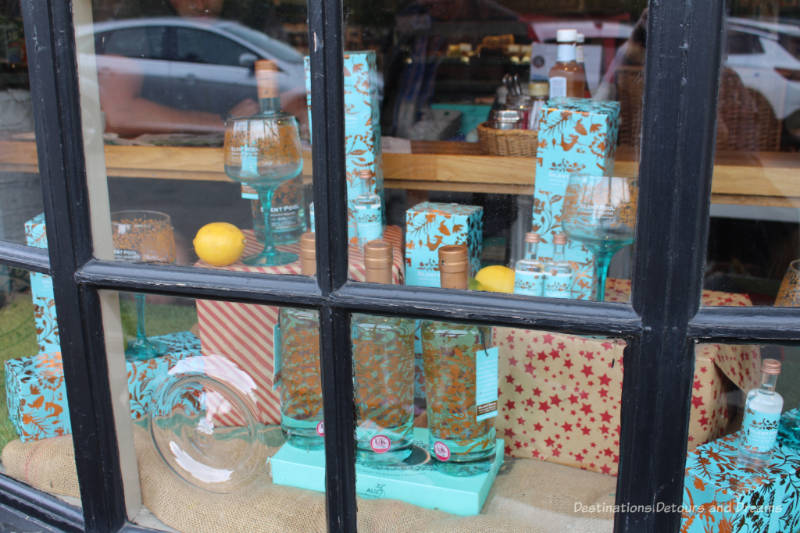 Turquoise and gold bottles and boxes of Silent Pool gin in a store window in England