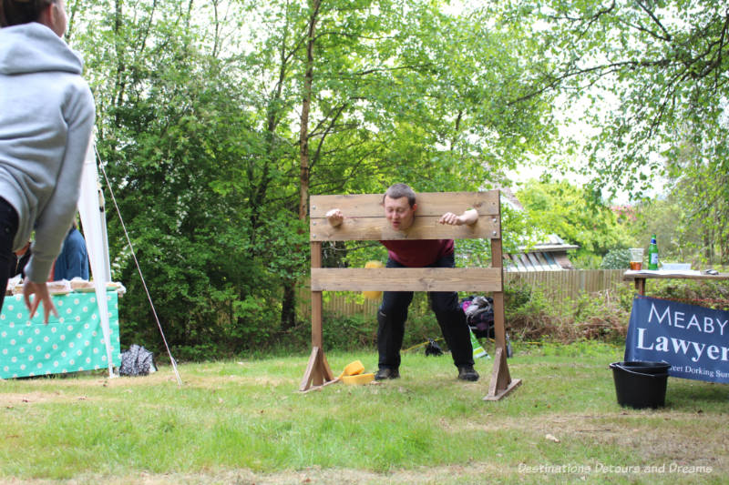 Man in stocks for wet sponge throwing game at an English village fête