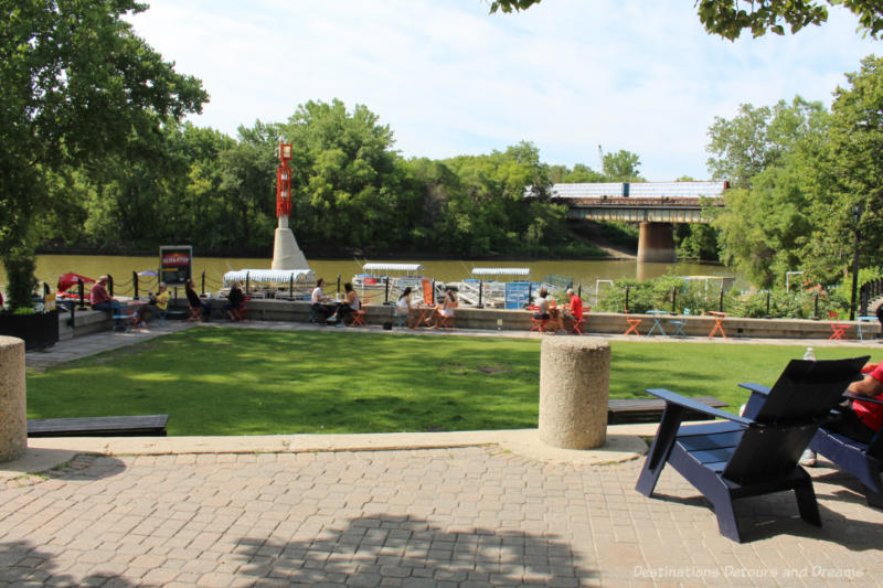 Chairs and bistro tables on The Forks patio overlooking the river