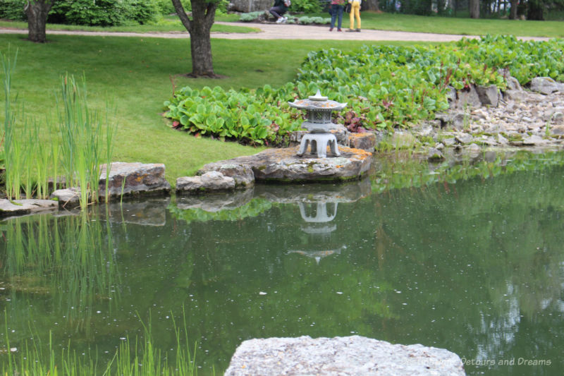 Japanese lantern at the edge of a pond in the Kurimoto Japanese Garden at U of A Botanic Garden