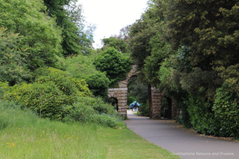 Shrubs and trees growing over a stone wall and doorway at Kew Gardens