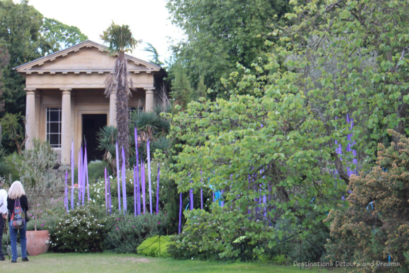 Stone temple amid shrubbery and Chihuly glass art at Kew Gardens