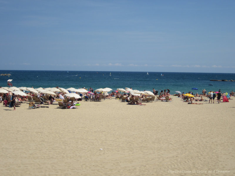 Barcelona beach with people sitting under umbrellas in the sand