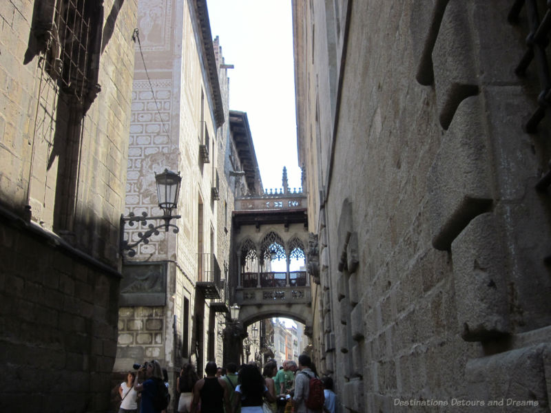 Narrow street lined with old brick buildings and a bridge between them in Barcelona Gothic area