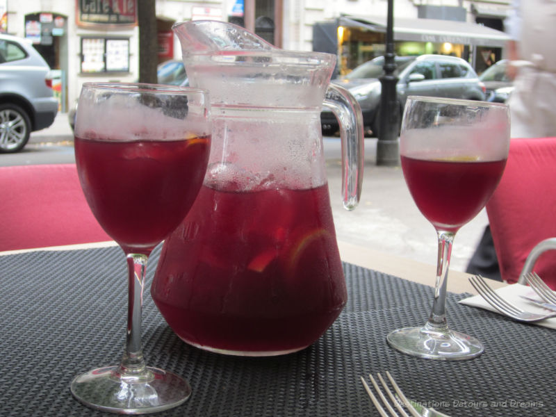 A glass pitcher of sangria with two filled glasses beside it