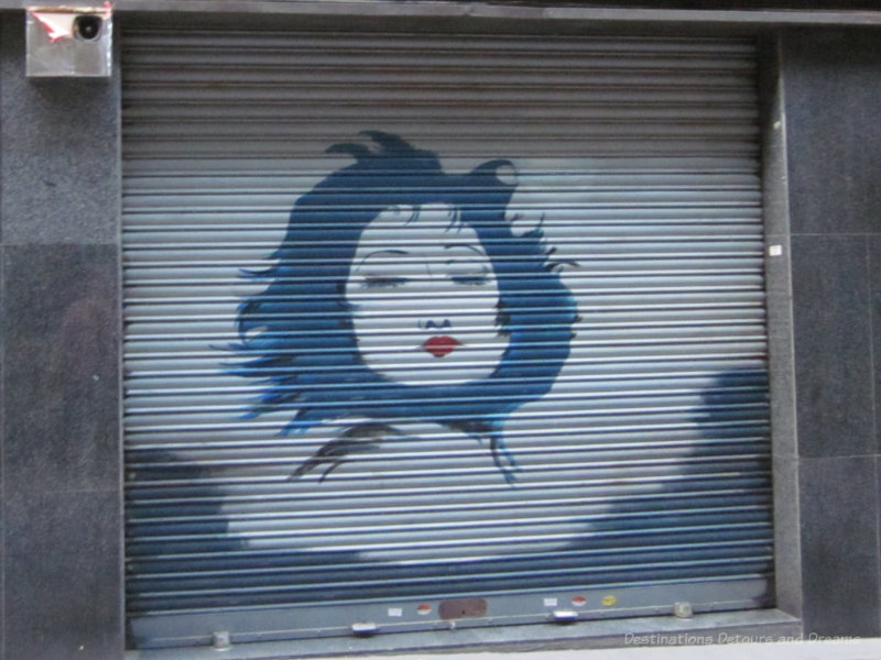 Painting of a woman's face on a metal shop shutter in Barcelona