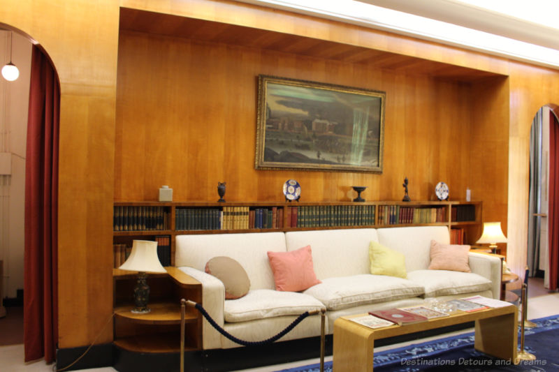 White sofa with wood wall and bookcase behind it at Eltham Palace