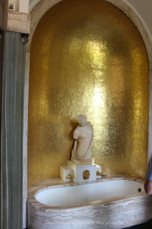 Marble bathtub with curved gold wall and Greek statue at Eltham Palace