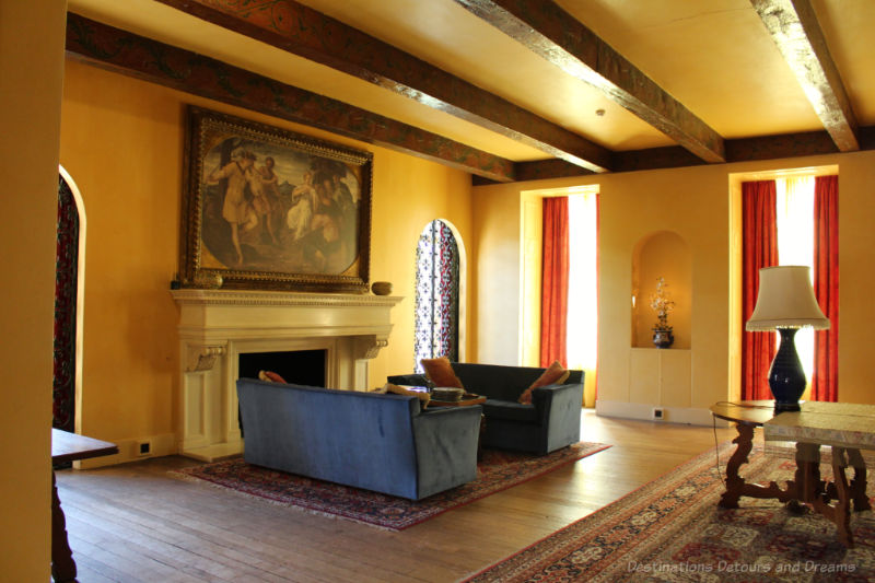 Blue sofas in front of a fireplace in a large room with yellow walls and high, wood-beamed ceilings at Eltham Palace