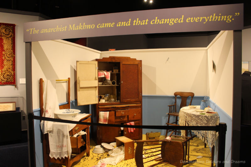 Display of a ransacked house with overturned chair, open cupboards, and broken dishes at the Mennonite Heritage Village