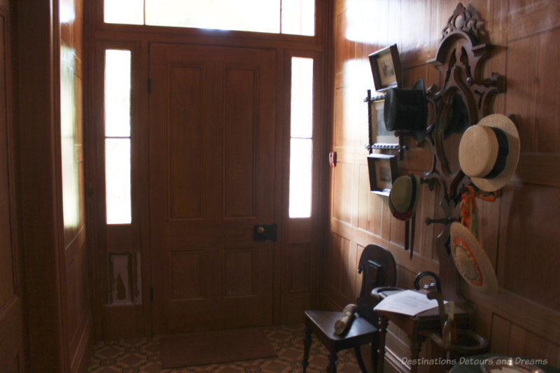 Front entryway, circa 1865, with wood-grained wallpaper, oilcloth floor, an hat rack.