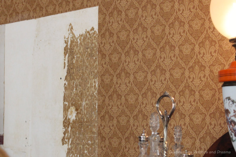 A section of wall at Ross Bay Villa with bits of the original 1800s wallpaper showing beside the recreated wallpaper on the rest of the wall