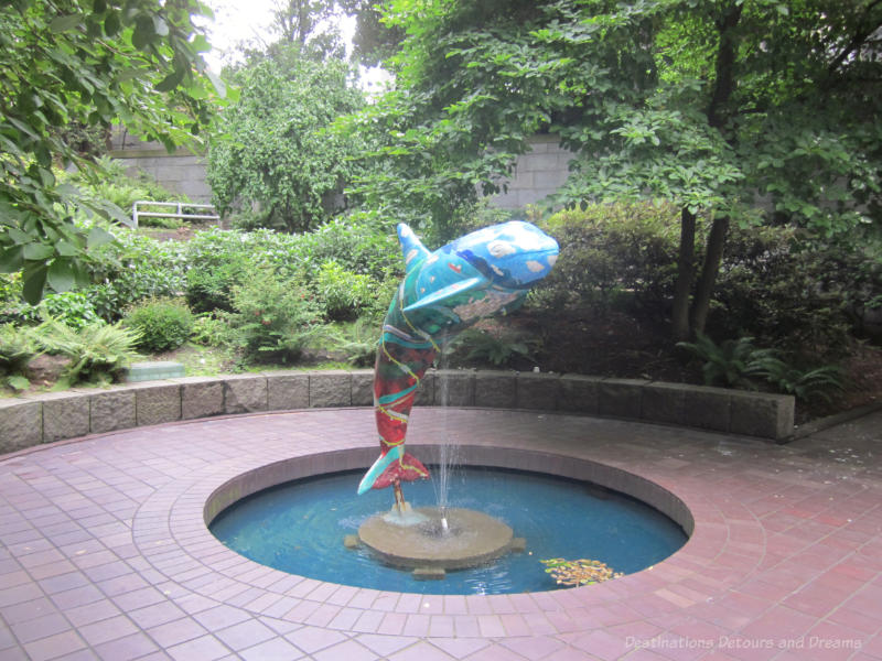 A public art piece in Vancouver features a colourfully painted orca jumping out of a fountain