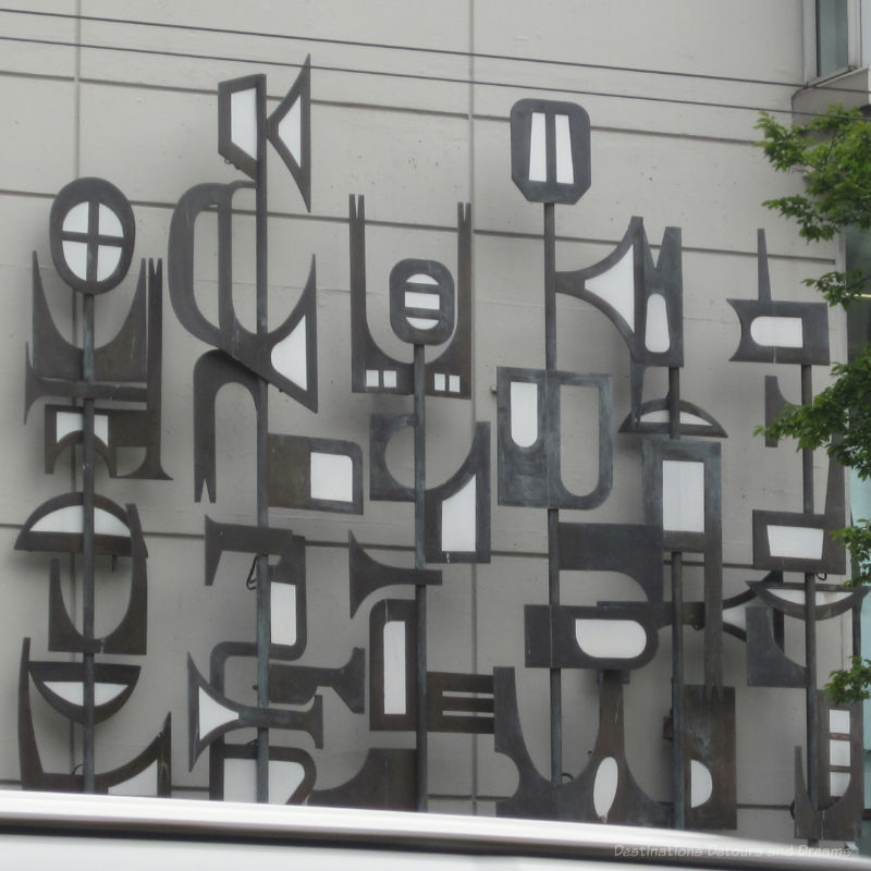 Abstract grey and white metal sculpture on wall of buidling