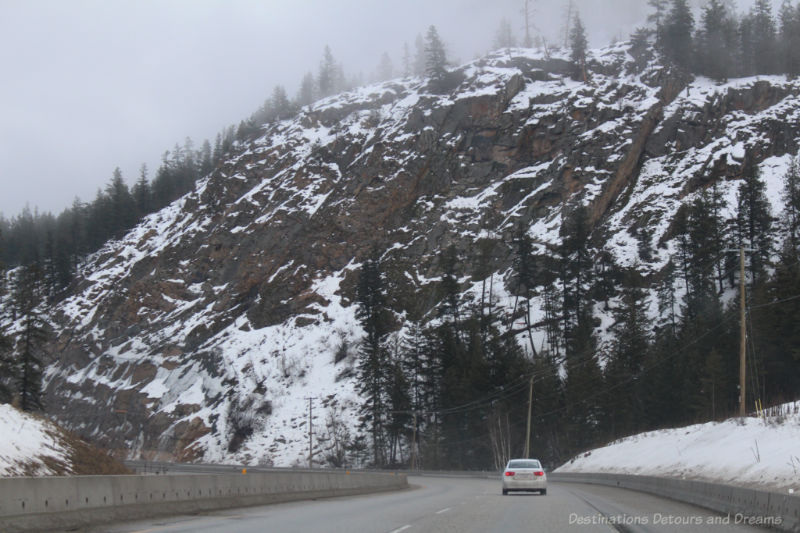 Mountain rock beside British Columbia highway partially covered with snow