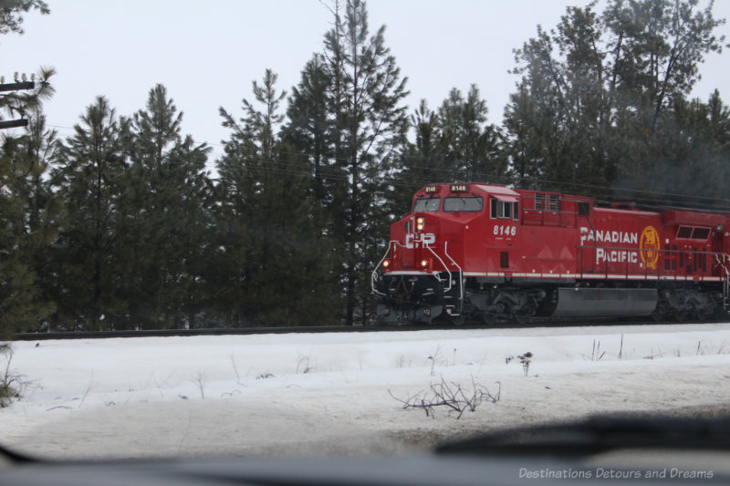 Canadian Pacific train engine driving past fir tress in British Columbia mountains