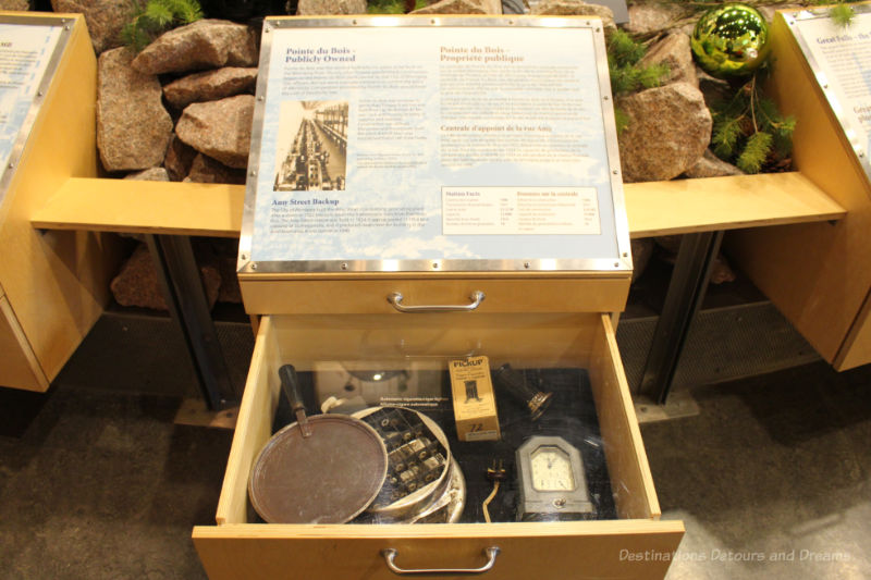 Open drawer under museum display showing electrical artifacts and electrical history information