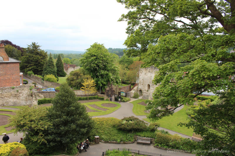 Looking down over green space, walkways, tress and the stone entrance wall to Guildford Castle