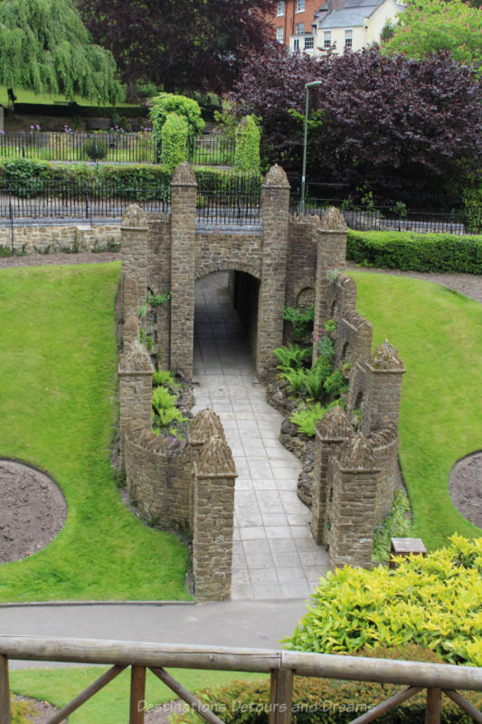 Stone walls with turret-like posts alongside walkway through Guildford Castle grounds