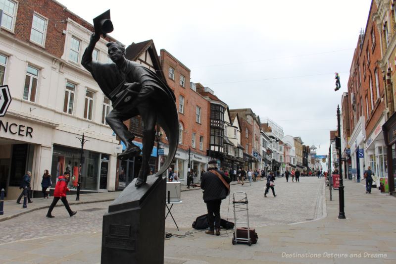 Cobblestoned pedestrian high street of Guildford with statue of the Surrey Scholar in the foreground