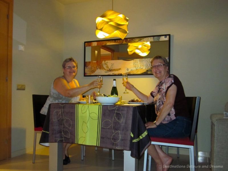 Two women having dinner and raising a glass of wine in their home exchange apartment