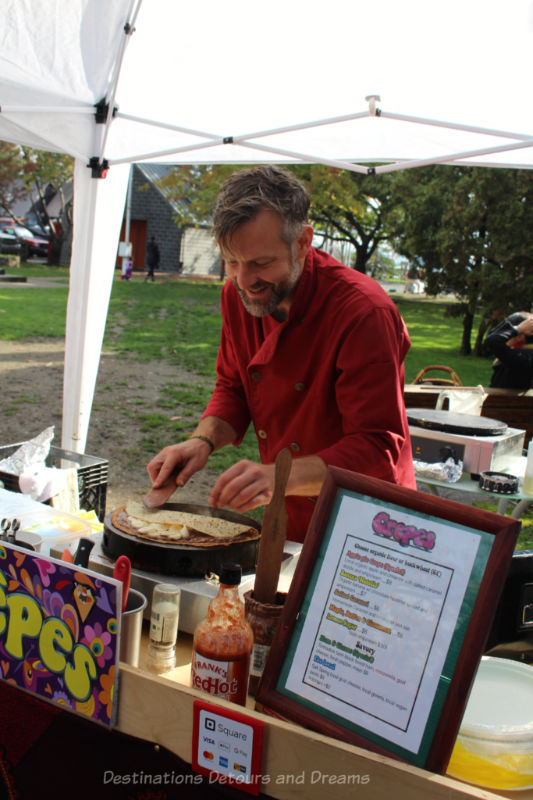 Man in red shirt cooking crepes on grill at a market