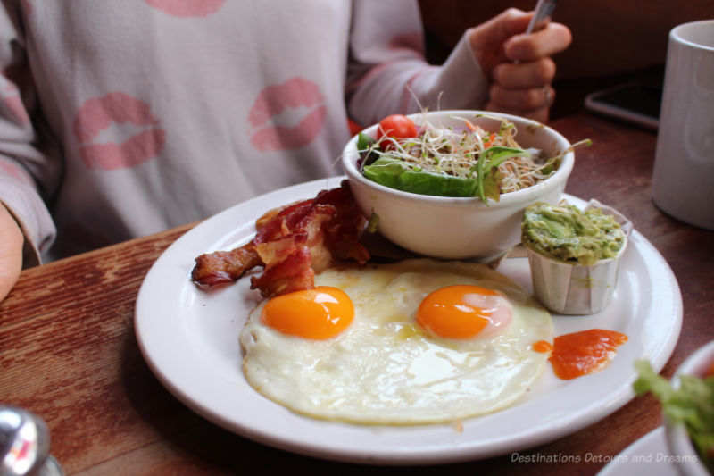 Brunch dish of eggs, bacon, greens, and guacamole