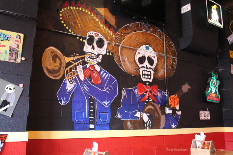 Painting on wall of El Loco Taco features musicians with blue suits, skull heads, and large sombreros